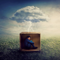 Surreal concept with a scared guy shelters inside a cardboard box. Introvert man caged by own fears as a thunderstorm cloud trapped him under the rain. Mysterious storm as emotional crisis symbol.